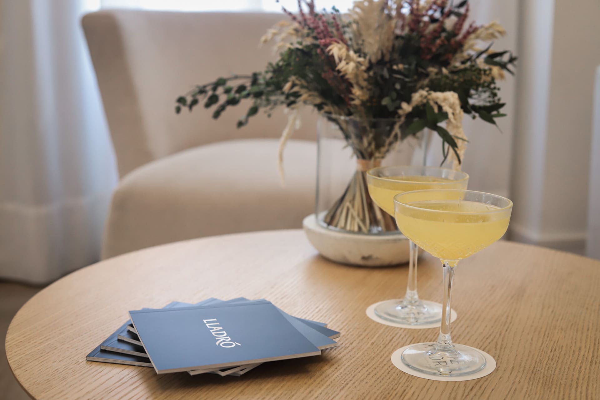 Dos cócteles amarillos en copas coupe sobre mesa de madera.