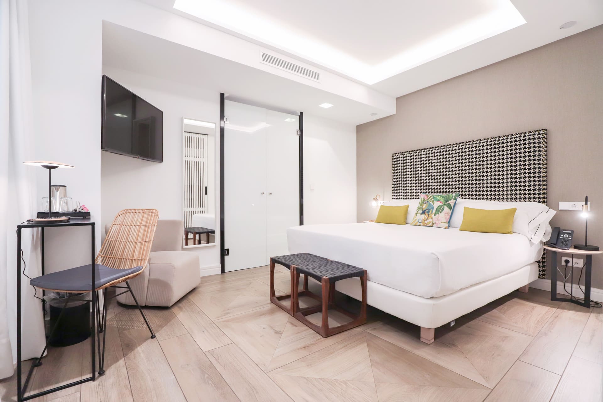 Habitación de hotel con cama king y cabecero estampado, TV y zona de descanso