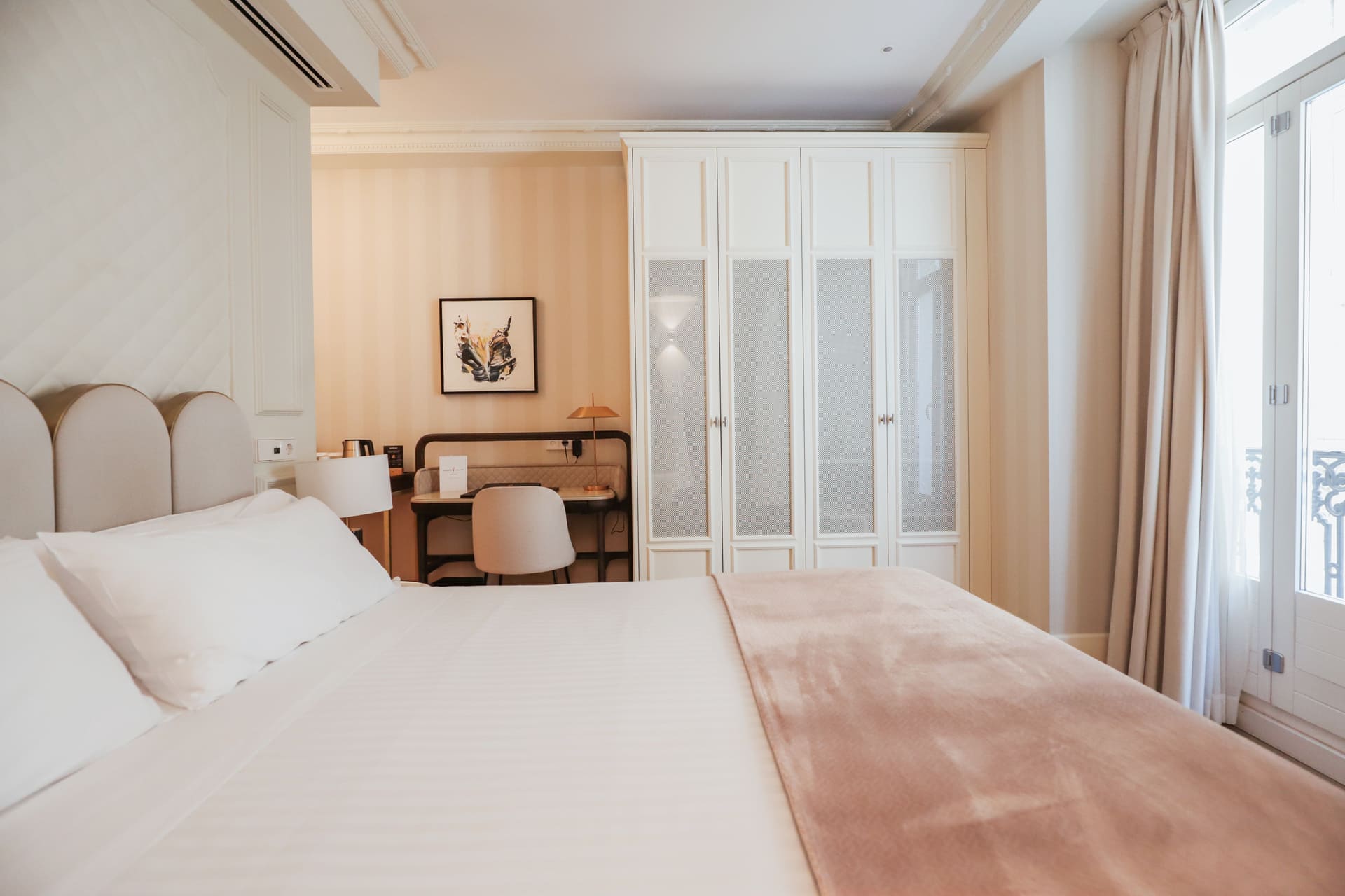 Habitación de hotel con cama grande, área de trabajo y armario blanco