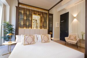 Habitación de hotel de lujo con cama king, cojines decorativos y panel dorado