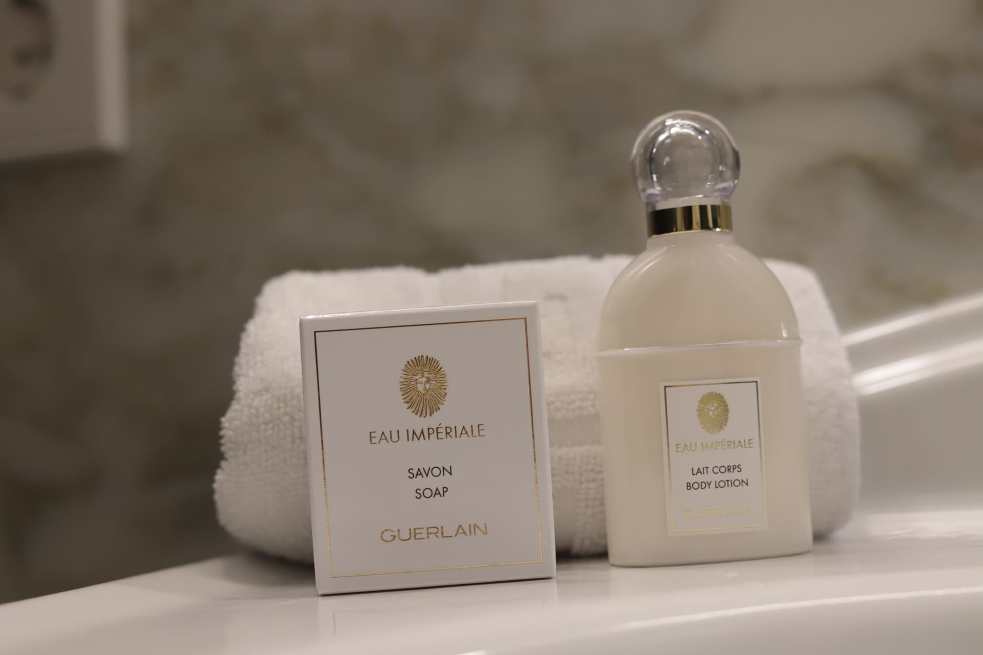 Set de amenities Eau Impériale de Guerlain: jabón y loción corporal junto a toalla blanca