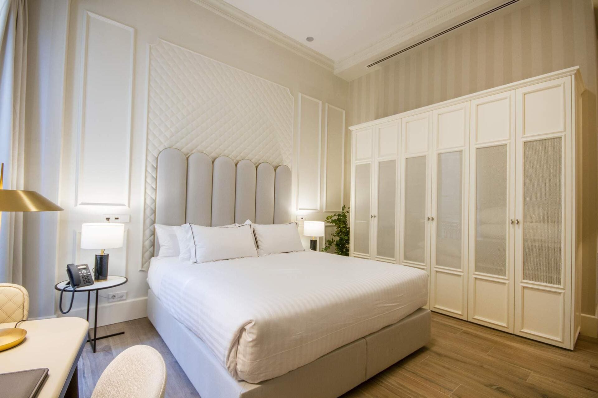 Habitación de hotel con cama king size, cabecero acolchado y armario empotrado.