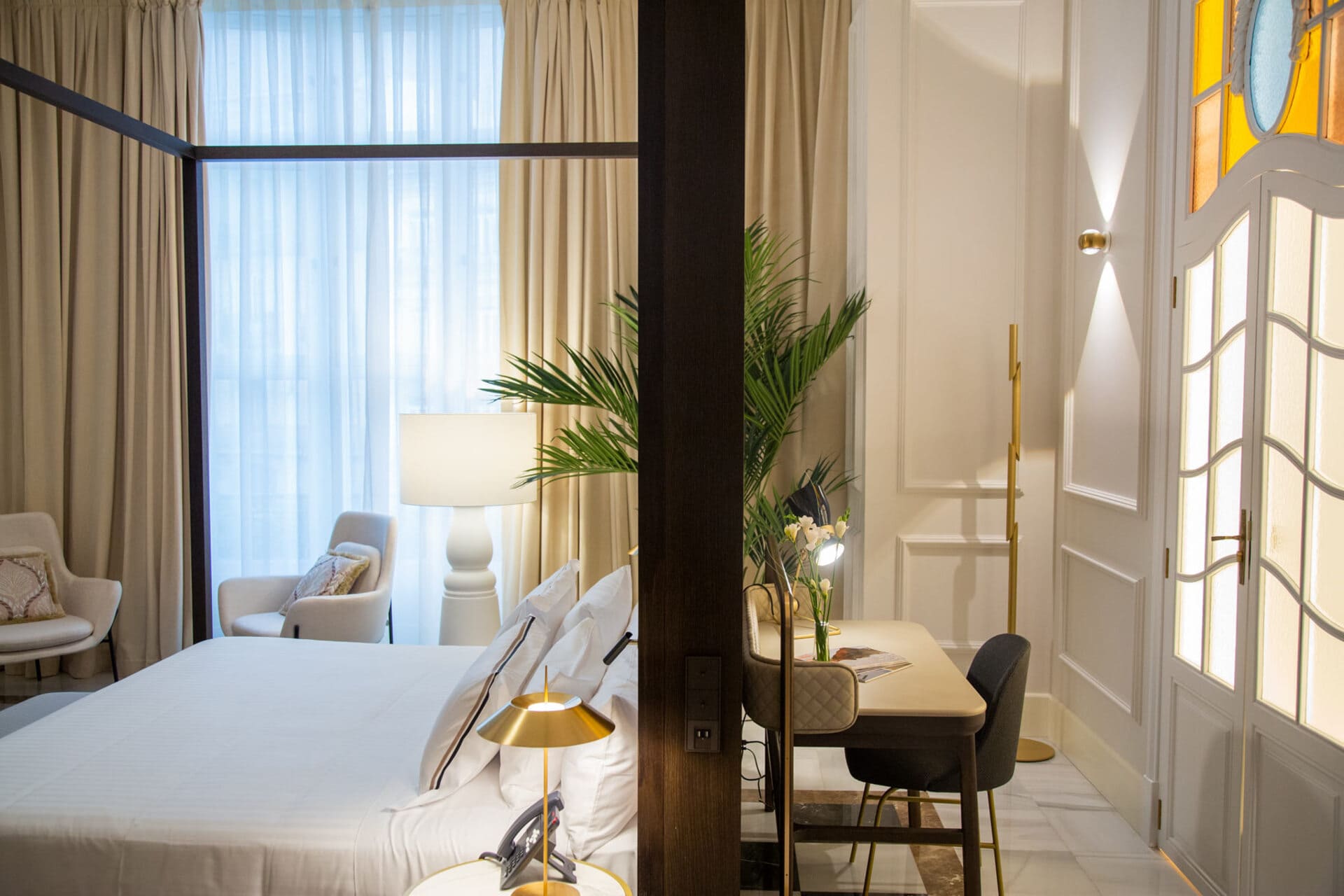 Habitación de hotel elegante con cama grande, zona de lectura y escritorio