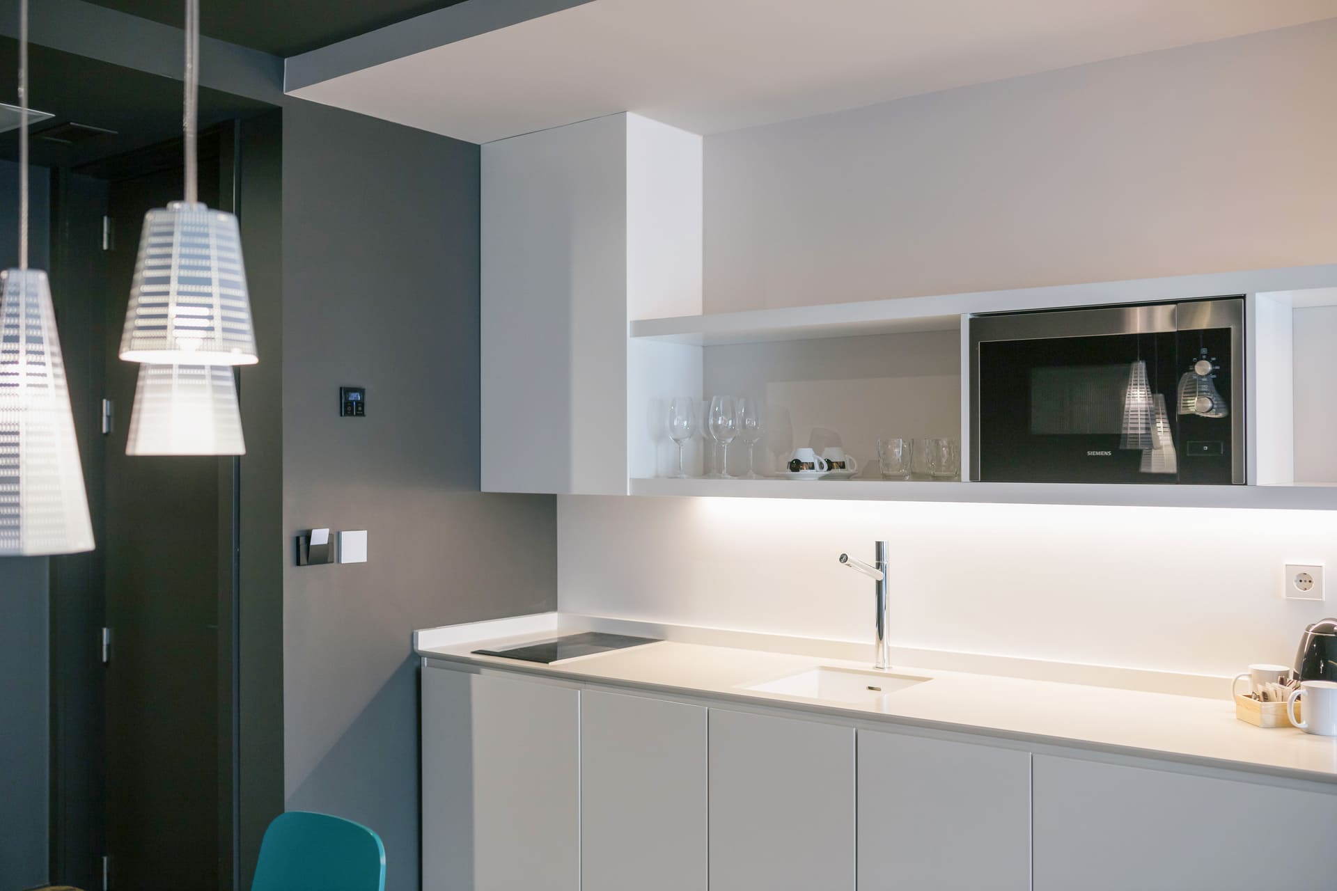 Cocina moderna de suite hotelera con fregadero, encimera blanca y microondas