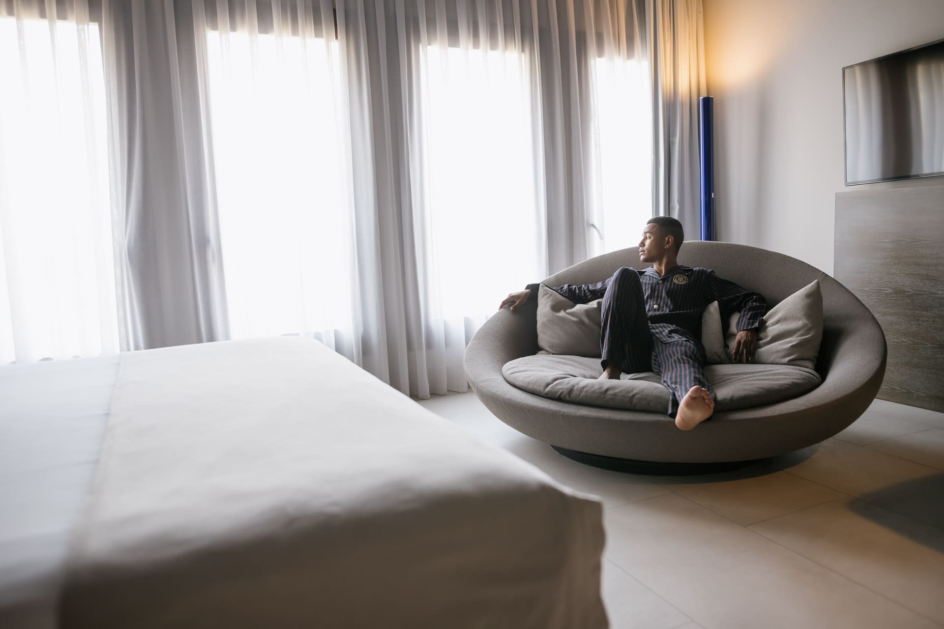 Hombre relajado en un sofá circular con cojines en habitación de hotel