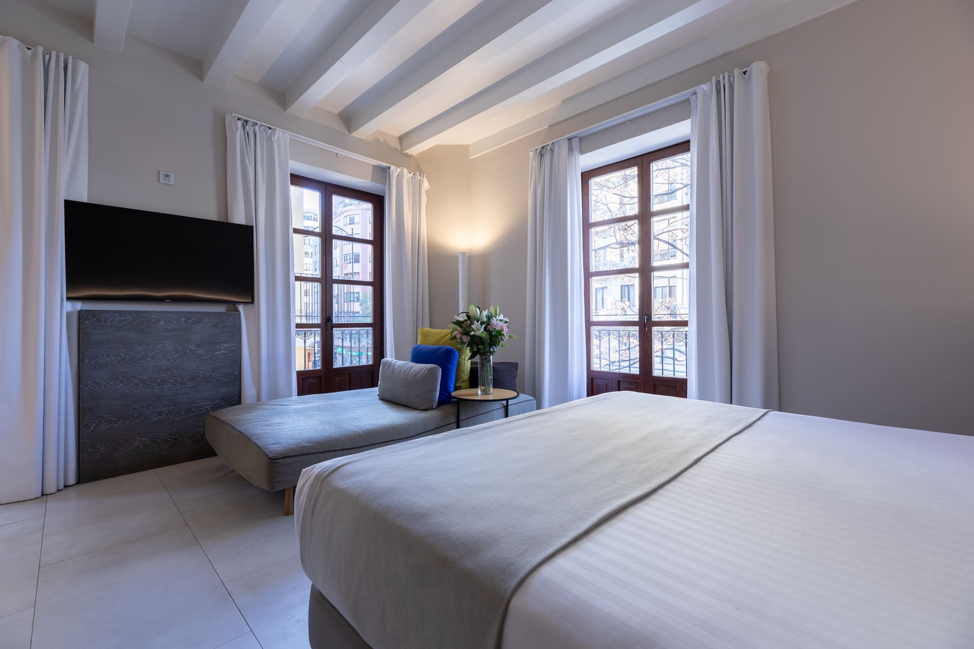 Habitación de hotel con cama king y zona de descanso junto a ventanales