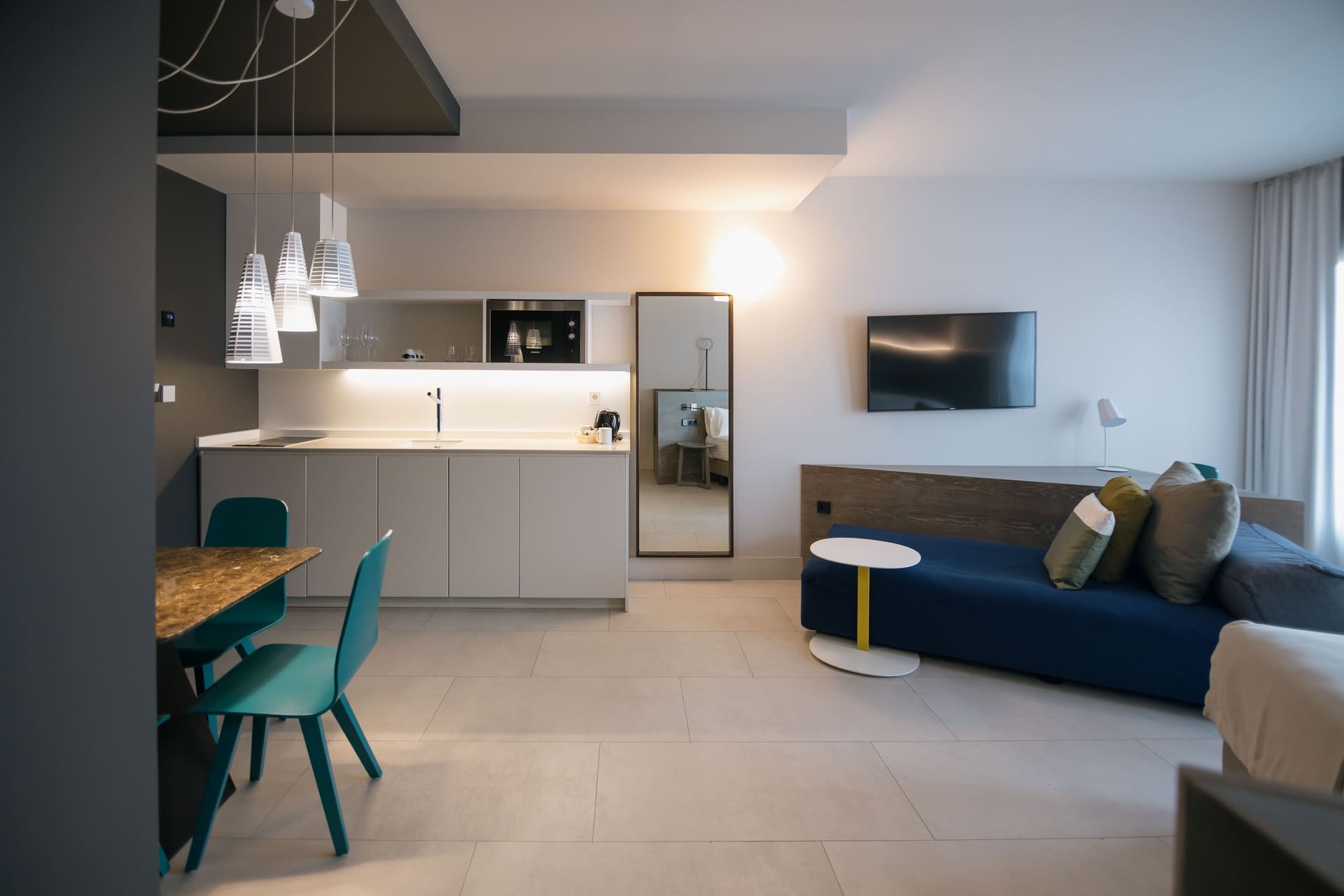 Suite con cocina integrada y sala de estar, mesa de comedor y sofá azul