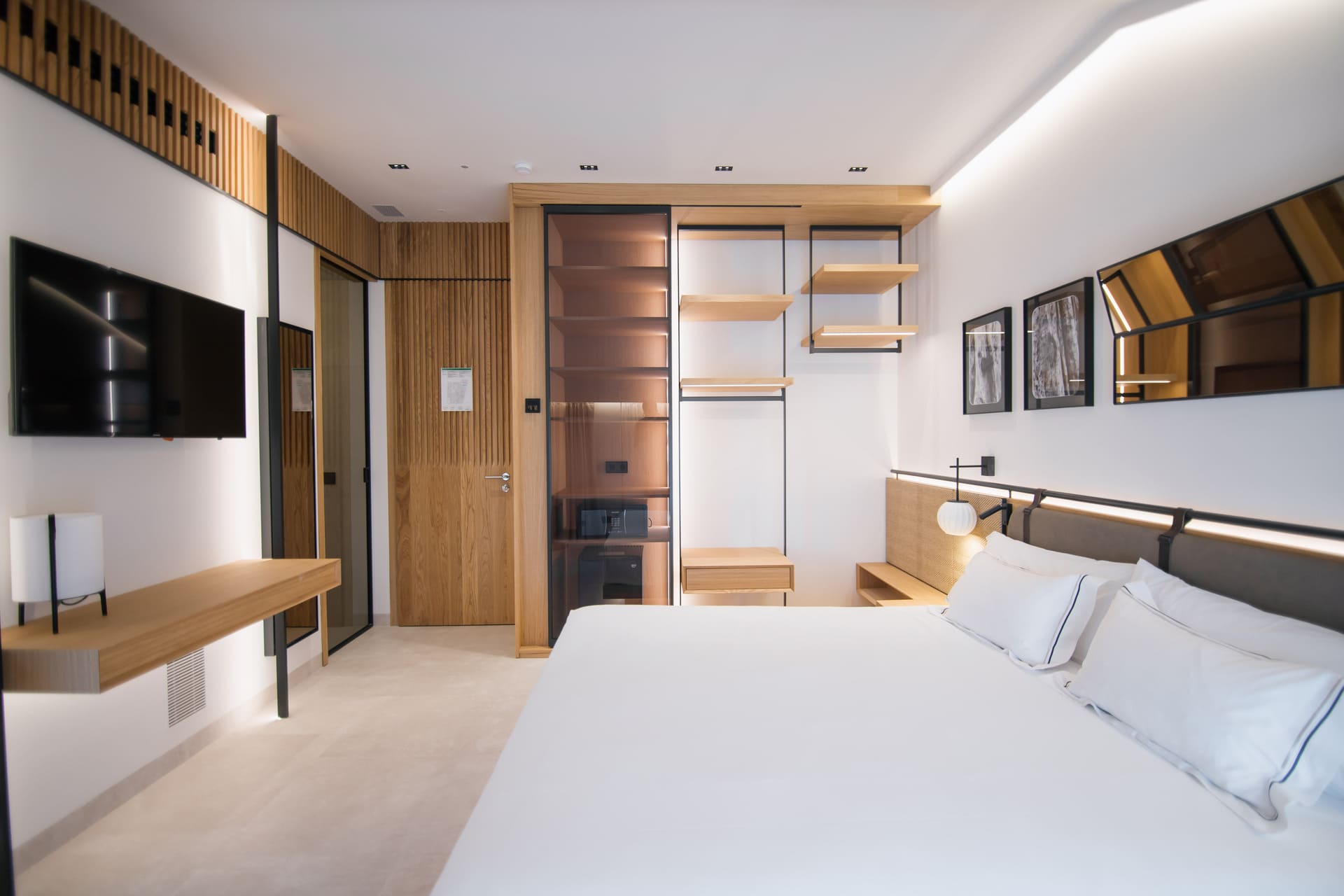 Habitación moderna de hotel con cama grande, TV, escritorio y armario abierto