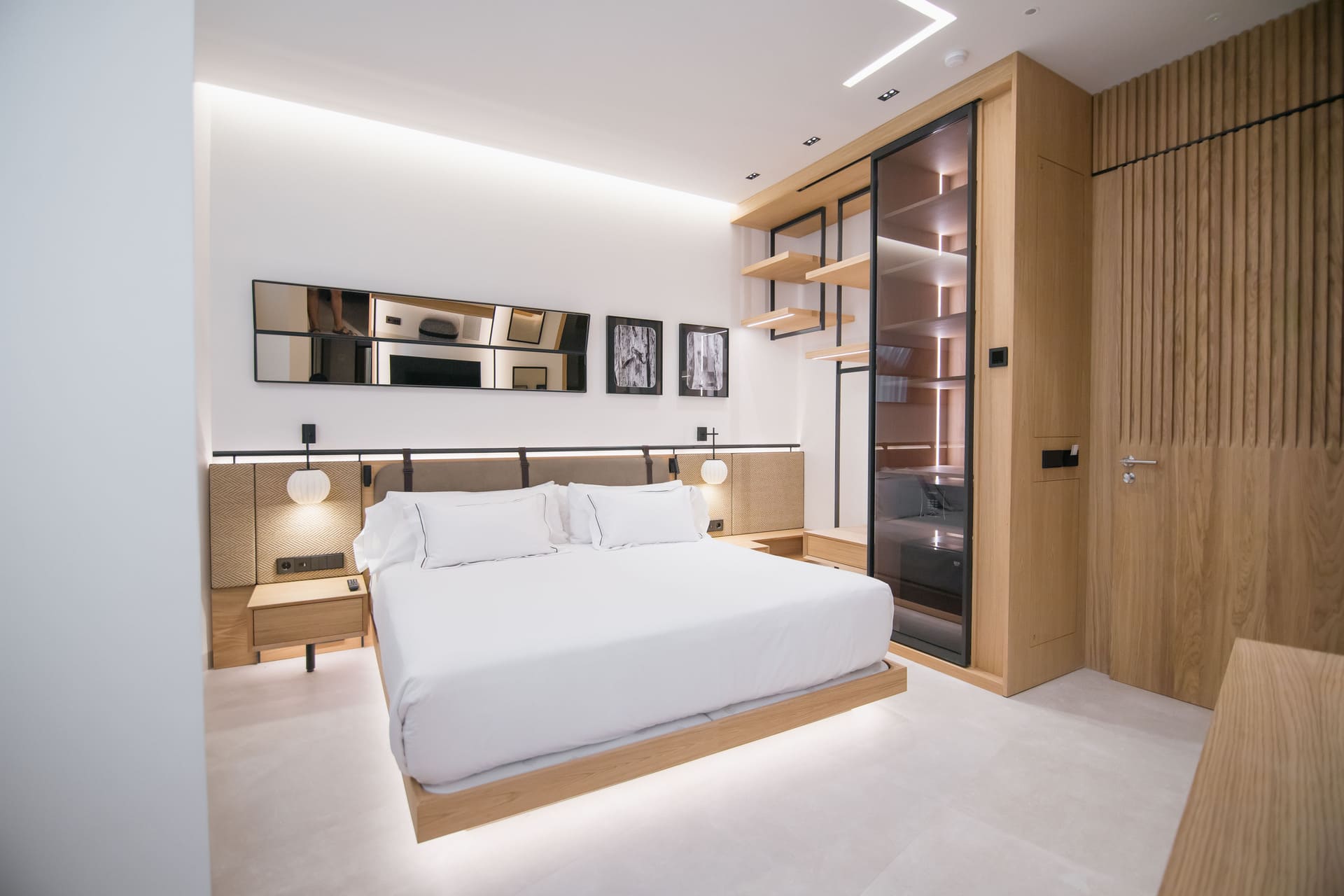 Habitación de hotel moderna con cama grande, cabecera acolchada y armario de madera