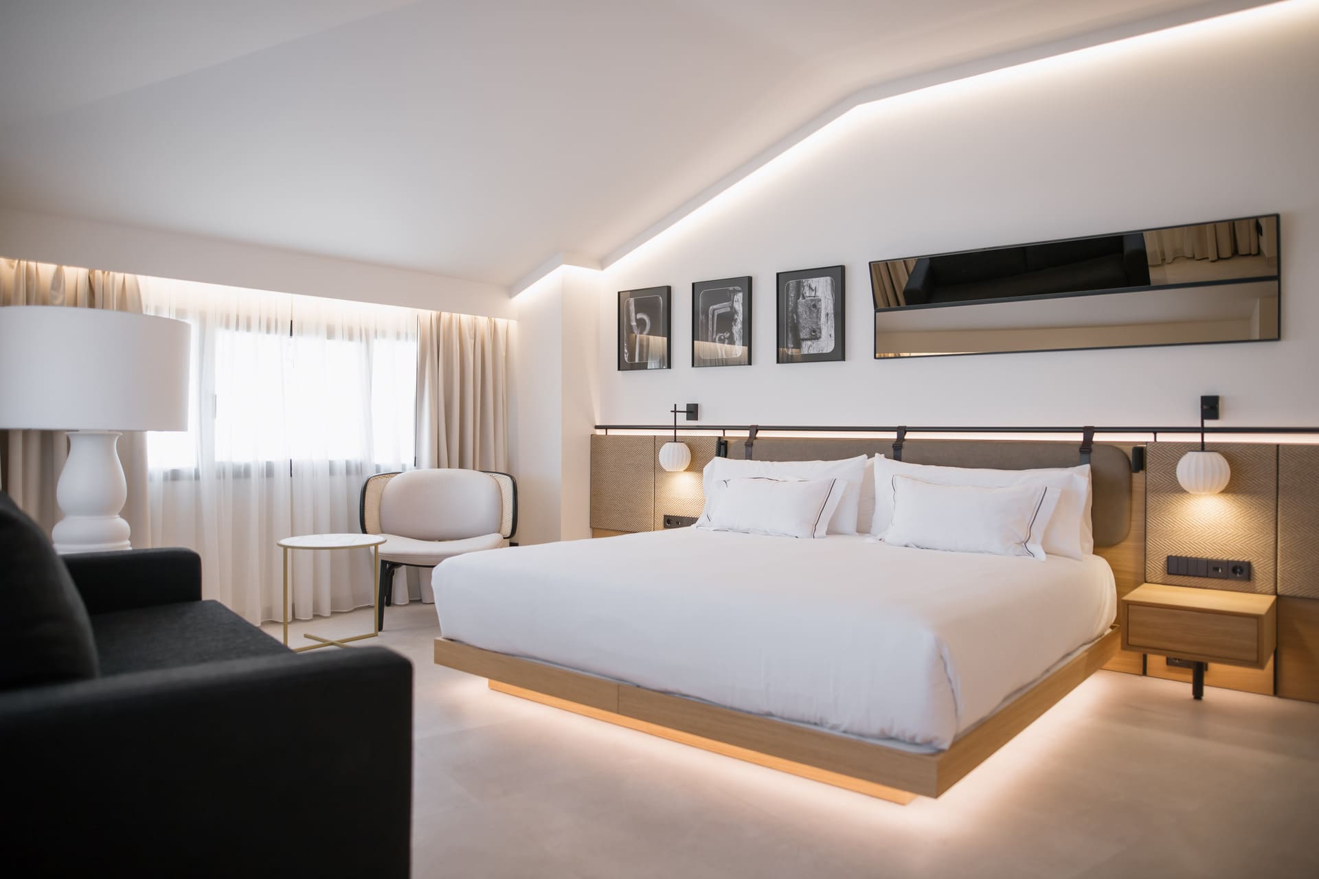 Habitación de hotel moderna con cama amplia, cabecero acolchado y iluminación ambiental.