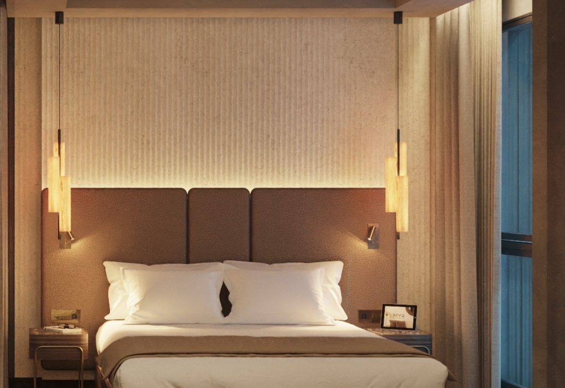 Habitación de hotel con cama amplia, cabecero acolchado y iluminación cálida