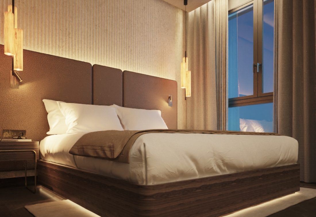 Habitación de hotel con cama king y cabecera acolchada, iluminación cálida