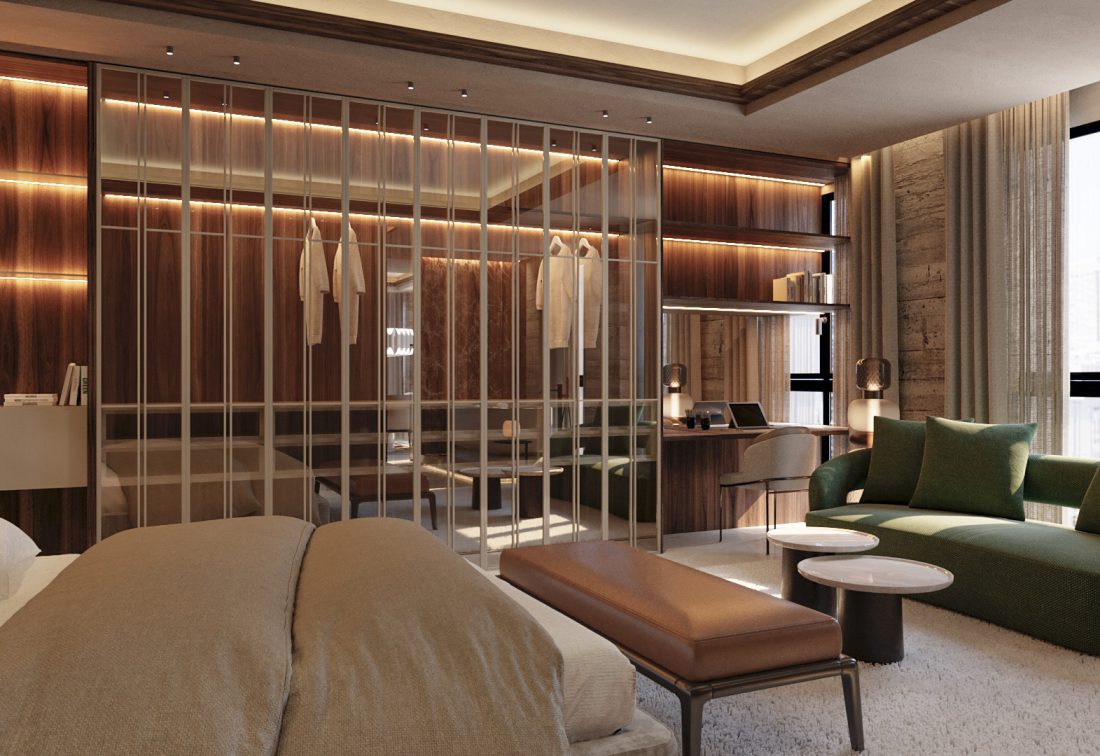 Suite de hotel con vestidor de vidrio, cama amplia y sala de estar con sofá verde.