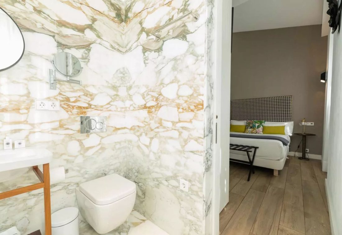 Baño de mármol en suite con lavabo y WC, que se abre a habitación con cama