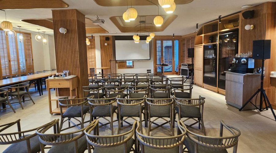 Sala de conferencias para eventos corporativos con proyector y sillas en filas.