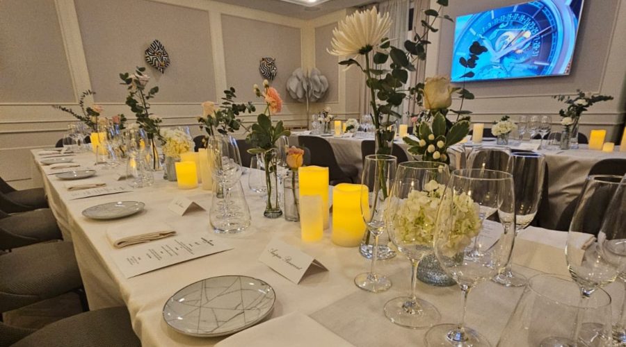 Banquete en salón de eventos con mesa larga, velas, copas y arreglos florales