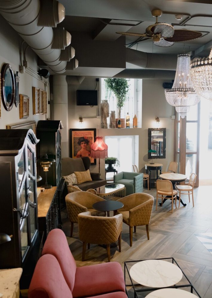 Interior de cafetería en Madrid con sofás rosa, sillas acolchadas y candelabros de cristal