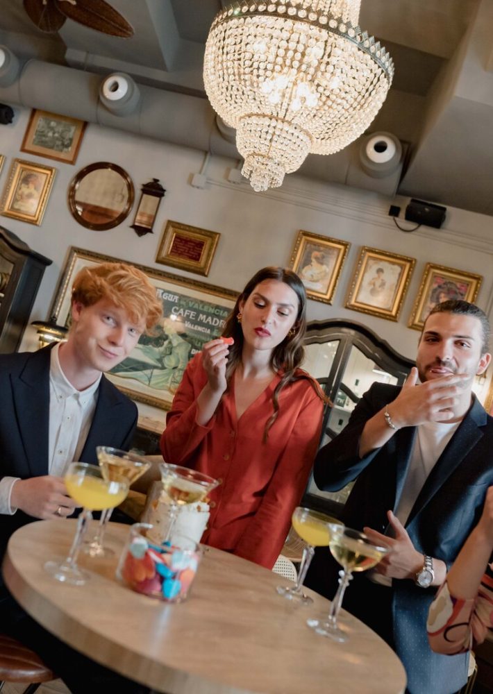 Grupo de tres amigos en Café Madrid, tomando cócteles alrededor de una mesa redonda