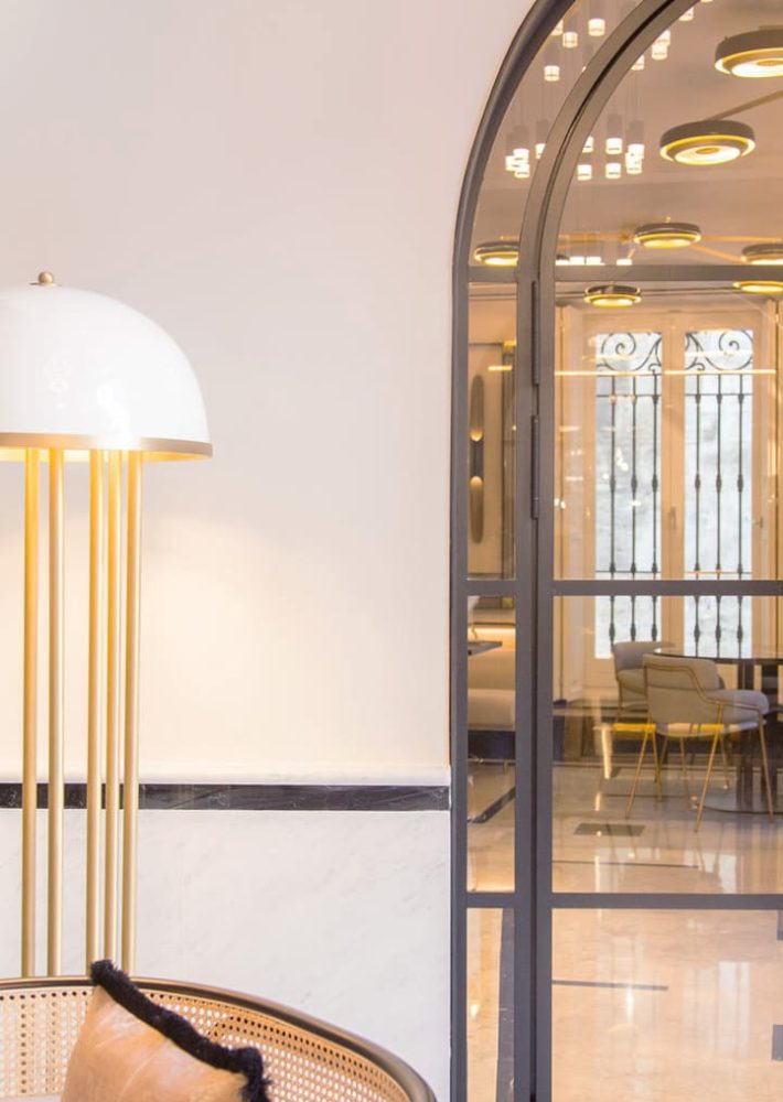 Vestíbulo de La Perfumería con lámpara dorada y puerta arqueada de cristal