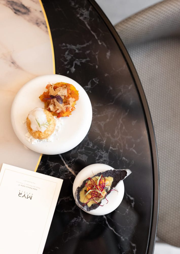 Aperitivos en dos platos blancos sobre mesa de mármol en La Perfumería