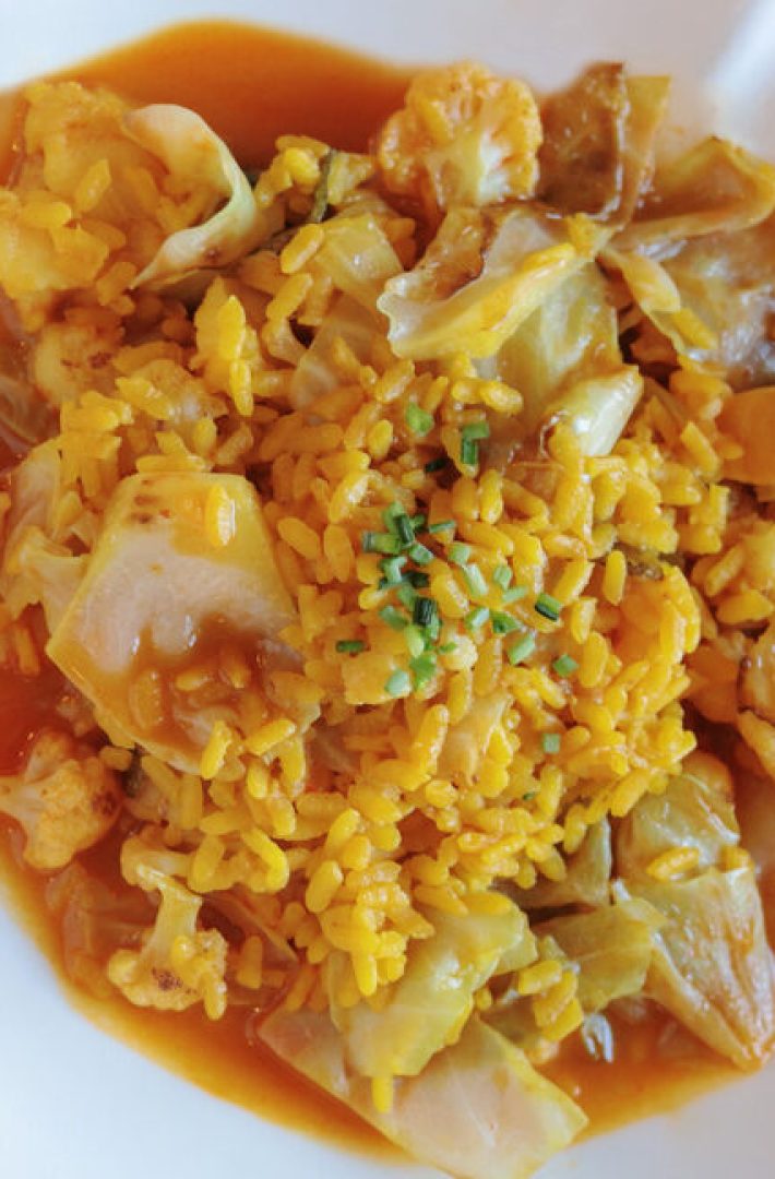 Yellow rice with vegetables on a white plate