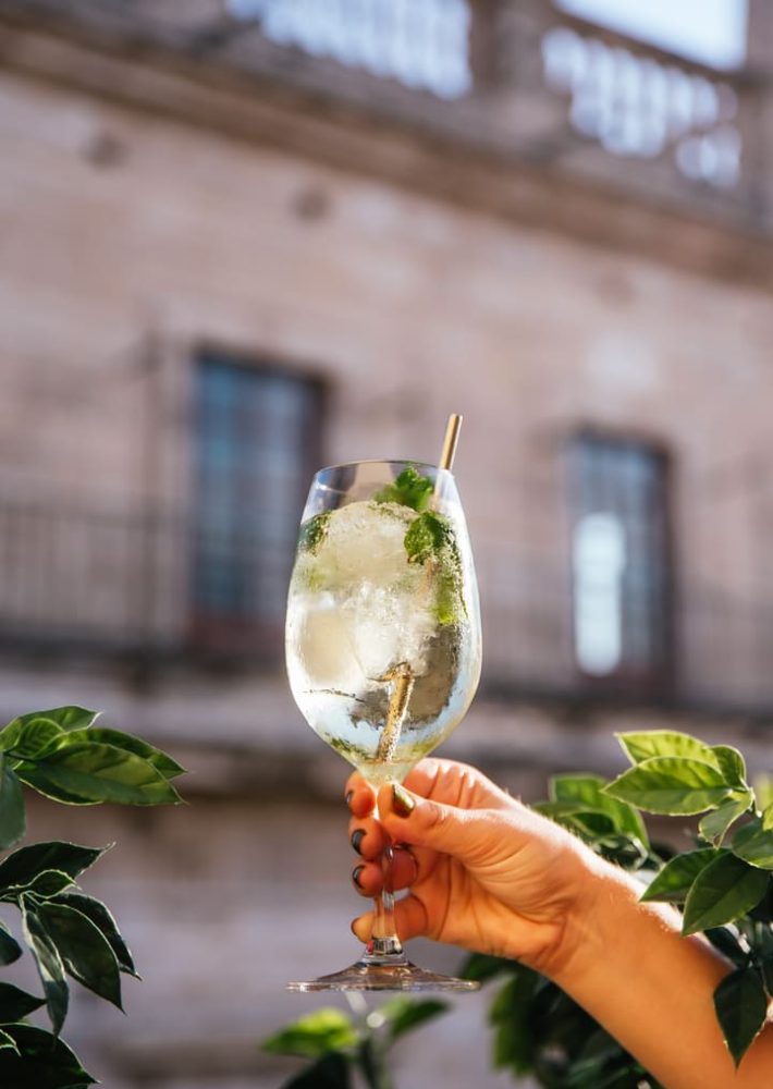 Cóctel con hielo y menta en copa de vino, en la azotea de Lladro Lounge