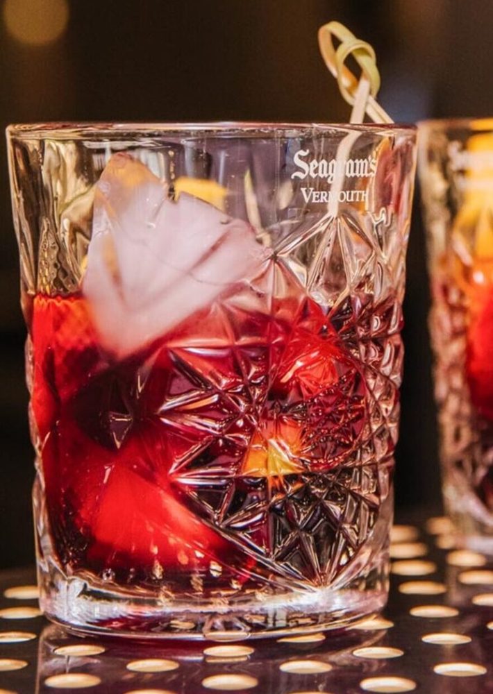 Cóctel rojo en vaso de cristal tallado con hielo en lounge bar