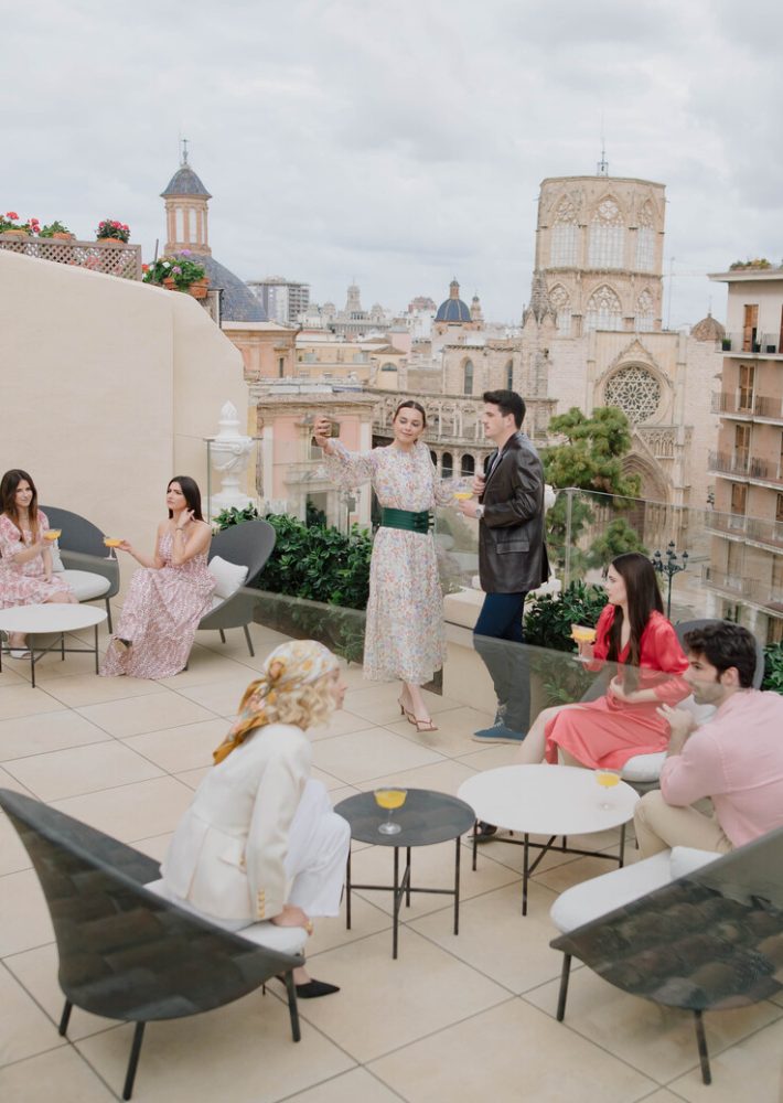 Grupo de personas en terraza de azotea, brindando con cócteles ante vistas de la ciudad