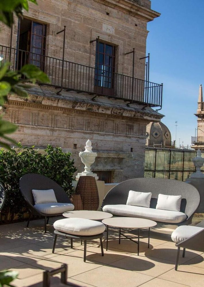 Zona de lounge en azotea con sofás y mesas redondas, cojines blancos