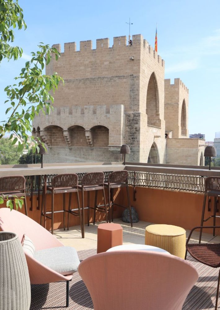 Terraza de hotel con sillones y barra, vistas a las Torres de Serranos en Valencia.