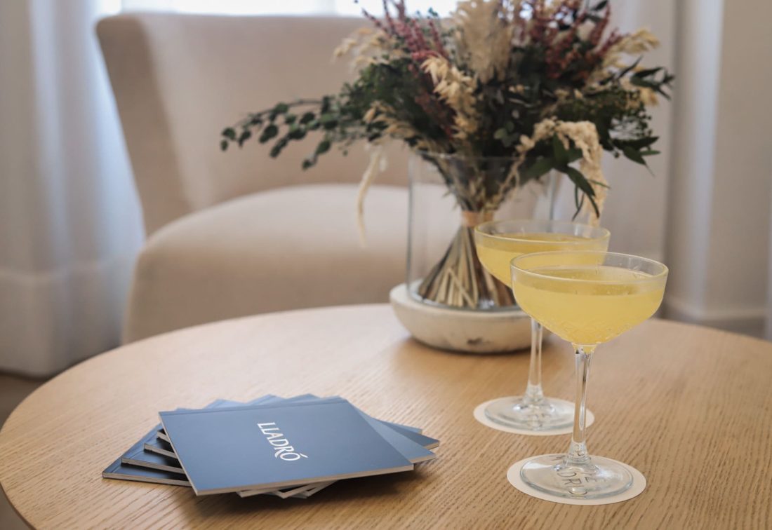 Dos cócteles amarillos en copas coupe sobre mesa de madera.