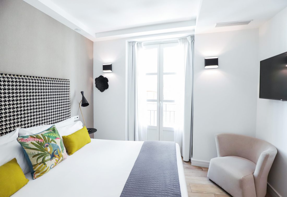 Habitación doble en Hotel Marqués House con cama grande, cabecero estampado y cojines amarillos