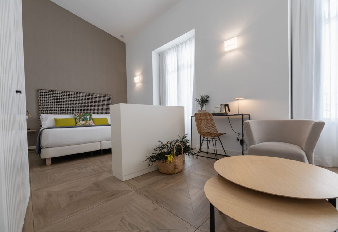 Habitación de hotel moderna con cama grande, área de trabajo y zona de estar.