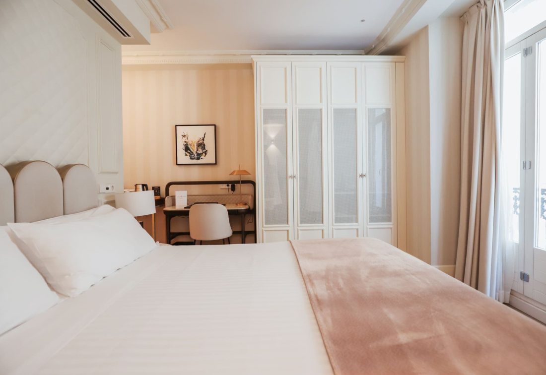 Habitación de hotel con cama grande, área de trabajo y armario blanco