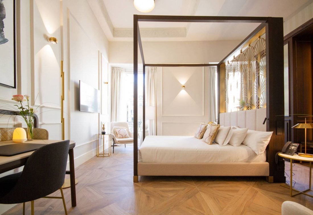 Habitación de hotel con cama de cuatro postes y zona de descanso