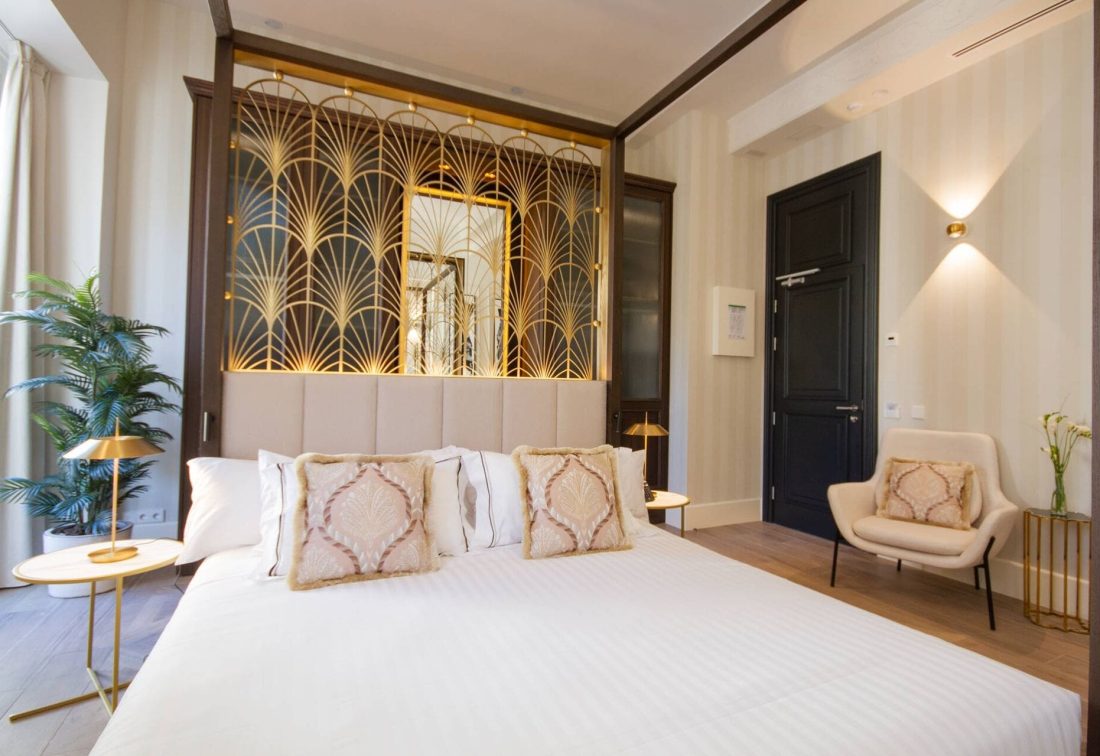 Habitación de hotel de lujo con cama king, cojines decorativos y panel dorado