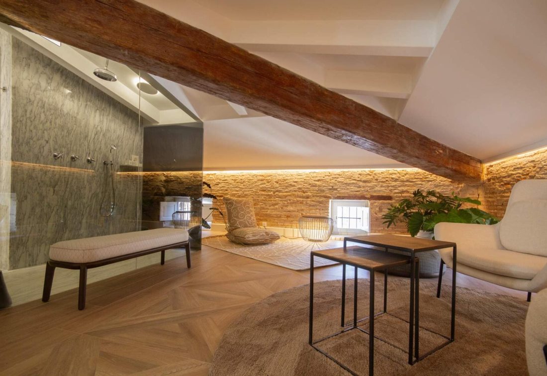 Sala de estar en ático con viga de madera expuesta, mobiliario moderno y plantas