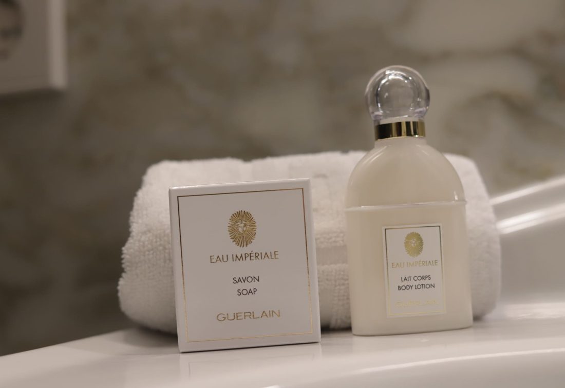 Set de amenities Eau Impériale de Guerlain: jabón y loción corporal junto a toalla blanca