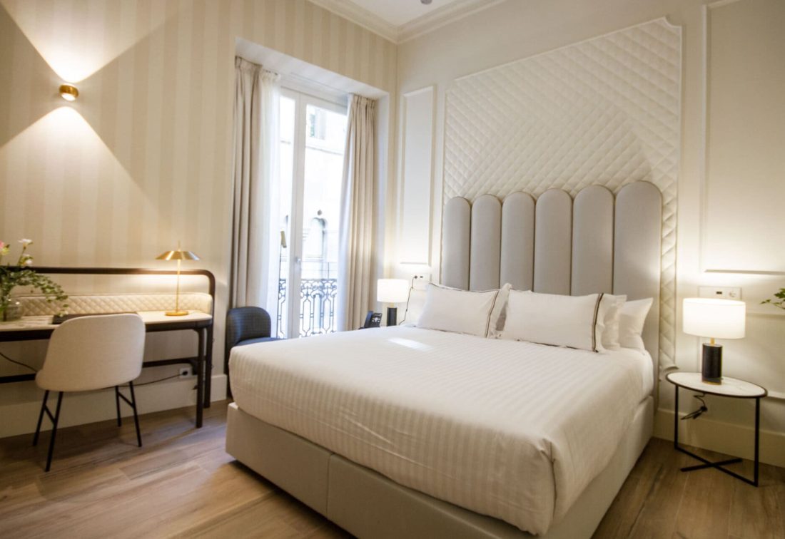 Habitación de hotel con cama king size, cabecero acolchado y escritorio