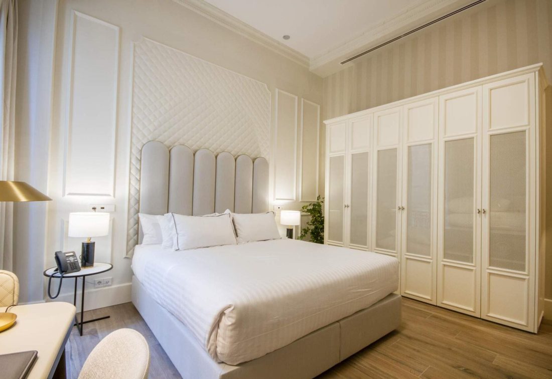 Habitación de hotel con cama king size, cabecero acolchado y armario empotrado.
