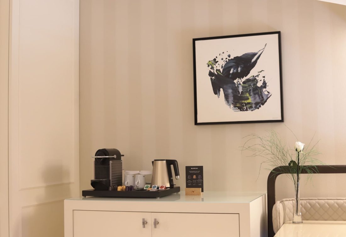 Zona de café Nespresso en habitación, junto a un cuadro abstracto