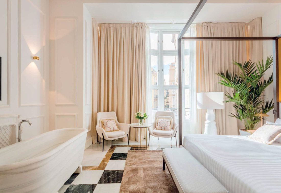 Habitación de lujo con bañera independiente y sala de estar junto a ventanales