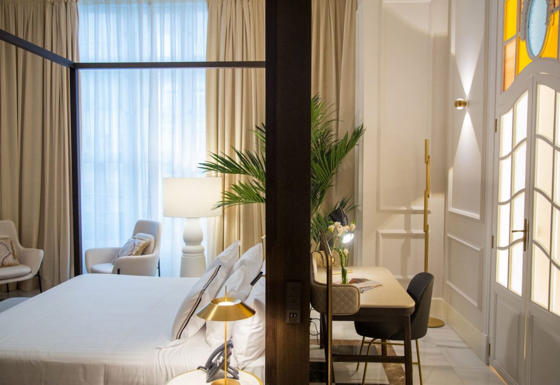 Habitación de hotel elegante con cama grande, zona de lectura y escritorio