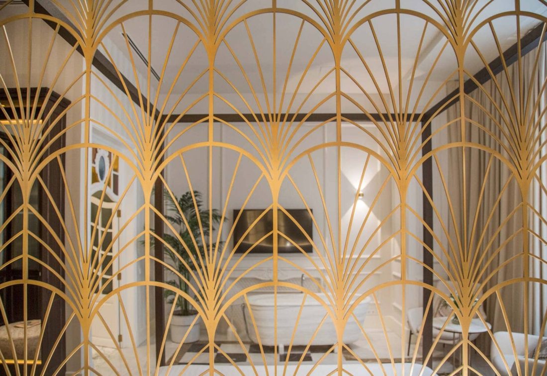 Pantalla decorativa dorada con diseño en abanico en habitación de hotel