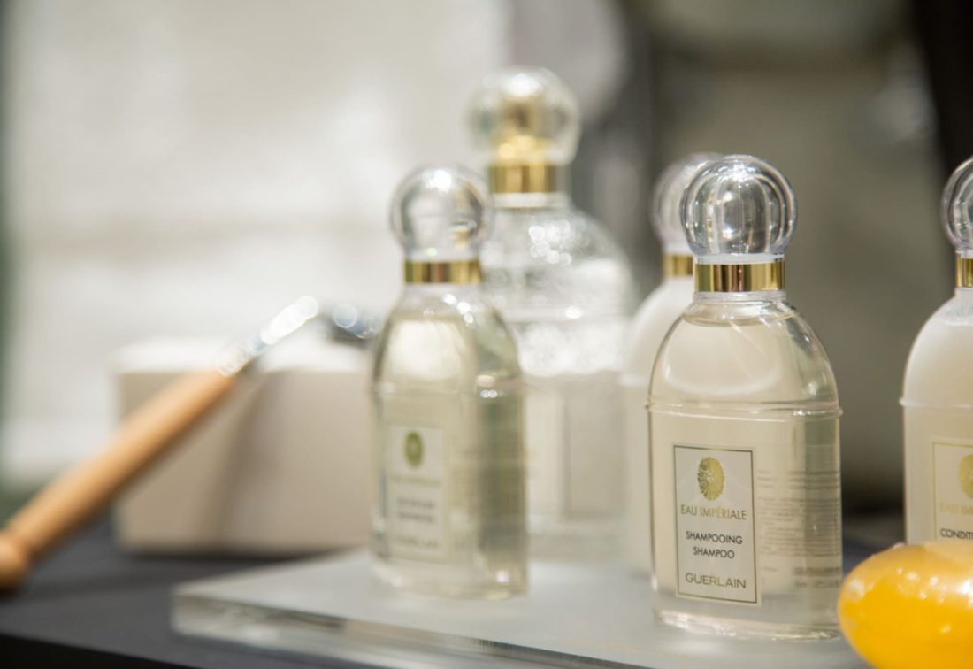 Botellas de aseo transparentes con tapón de cristal en tocador de hotel