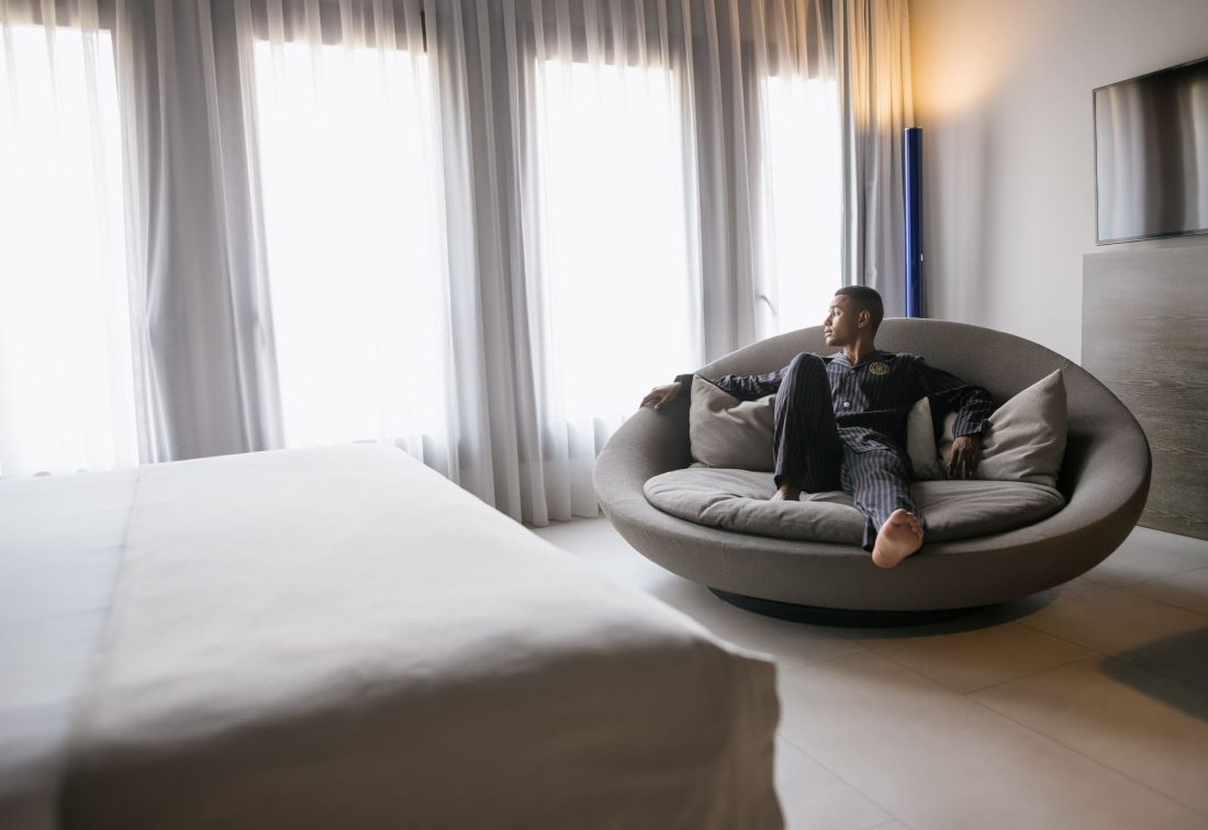 Hombre relajado en un sofá circular con cojines en habitación de hotel