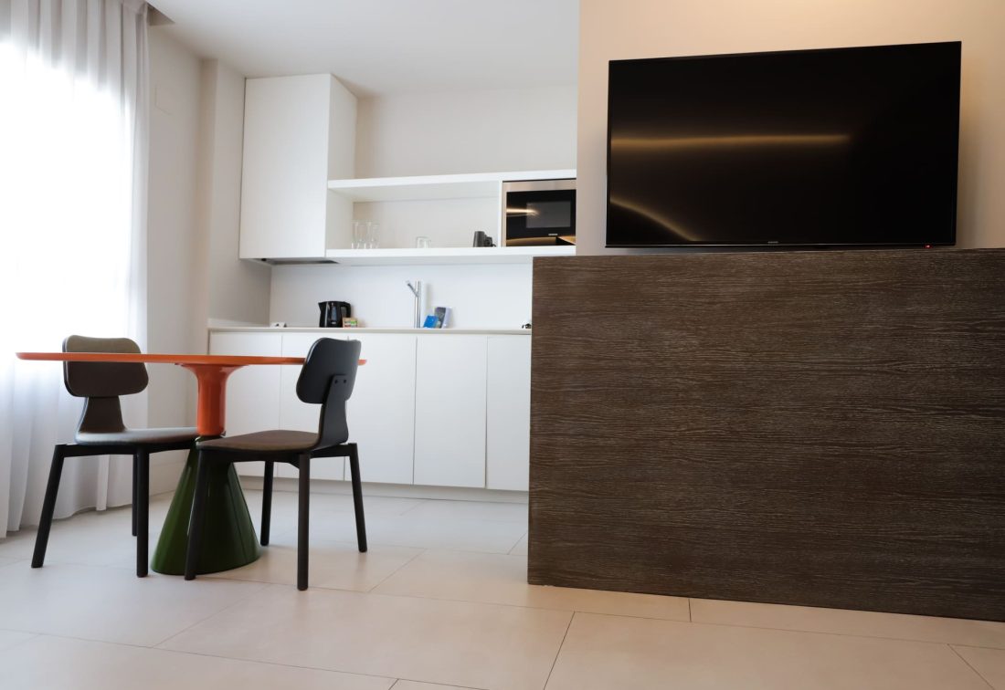 Zona de cocina abierta y comedor en habitación de hotel con mesa naranja