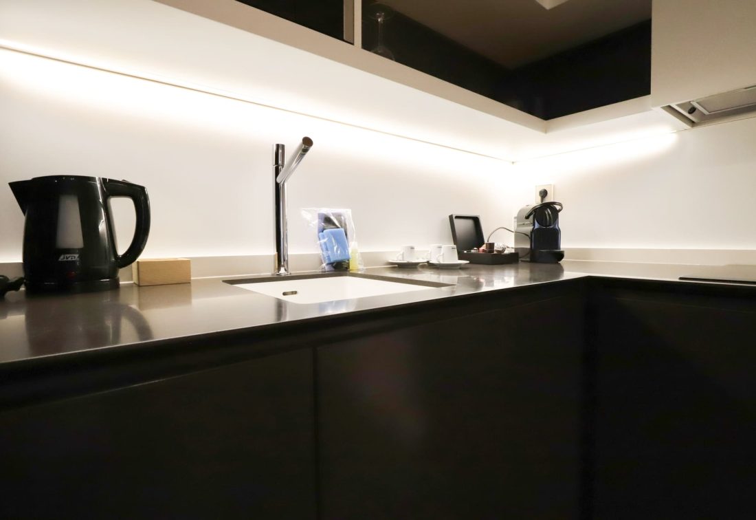 Cocina de hotel con fregadero, grifo moderno y hervidor eléctrico