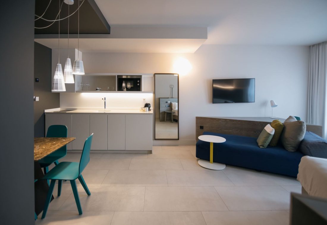 Suite con cocina integrada y sala de estar, mesa de comedor y sofá azul