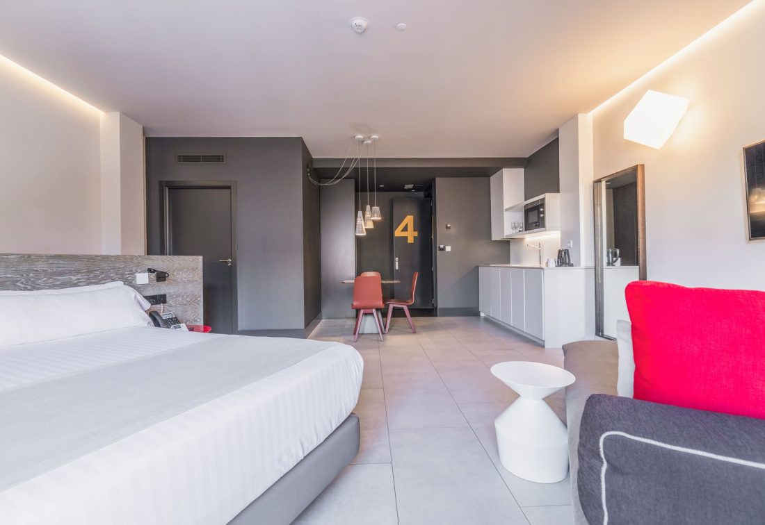 Habitación de hotel moderna con cama amplia, zona de cocina y comedor